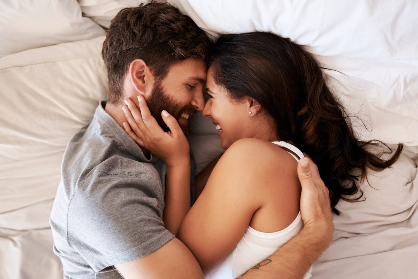 Smile, bed and happy couple hug, relax and spending lazy morning together, bonding and intimacy on Spain vacation. Happiness, marriage and top view of romantic man, woman or people embrace in bedroom Smile, bed and happy couple hug